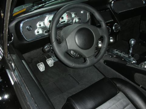 Black custom car cockpit with sport steering wheel and drilled aluminum pedals