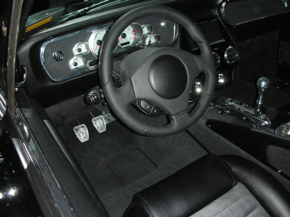 Black custom car cockpit with sport steering wheel and drilled aluminum pedals