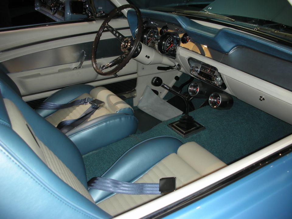 Vintage car interior with blue and white seats, wood wheel and chrome shifter