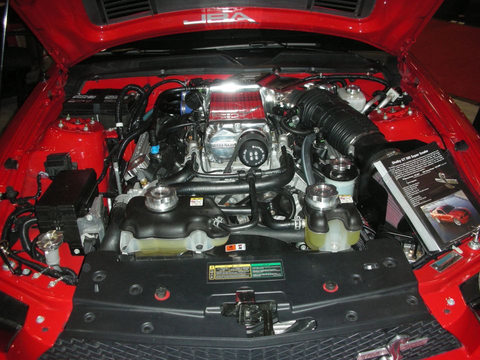 Engine bay of a red Mustang with supercharger and JBA branding