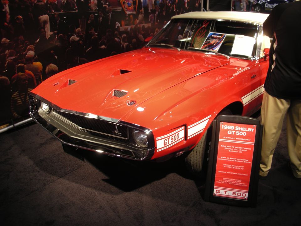 Red 1969 Shelby GT500 convertible at an auction with info placard