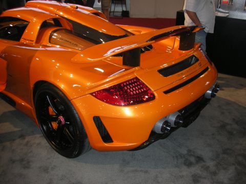 Rear quarter of an orange sports car with rear wing and quad exhaust