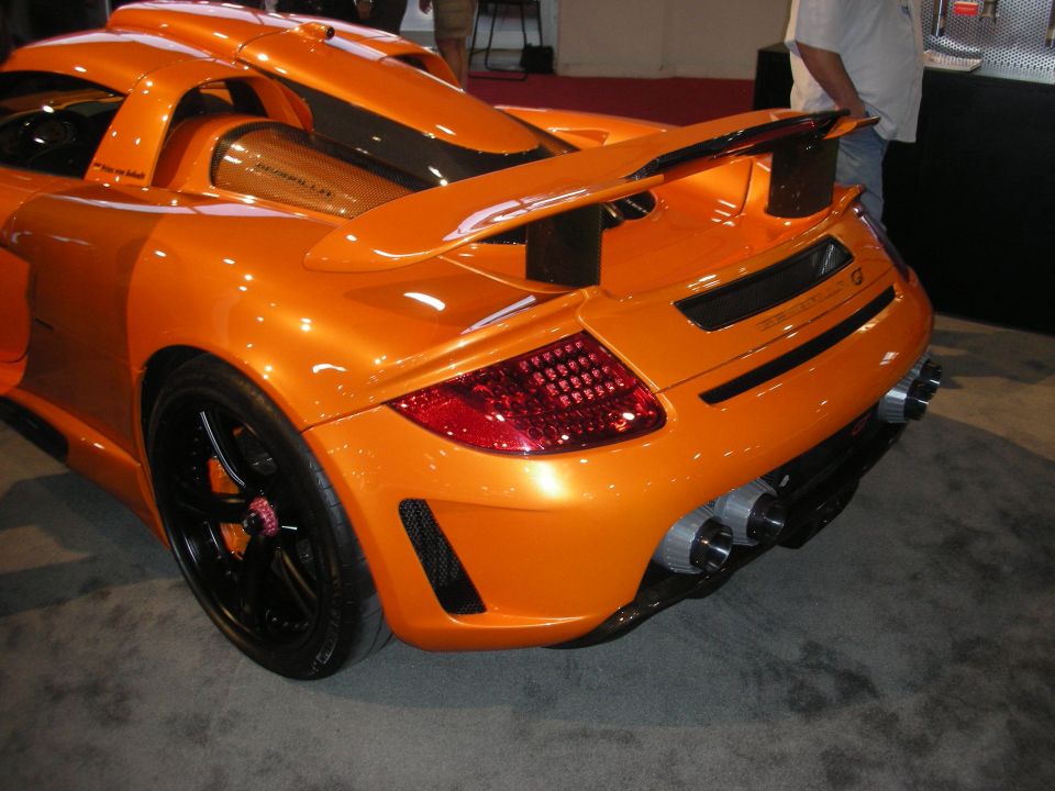 Rear quarter of an orange sports car with rear wing and quad exhaust