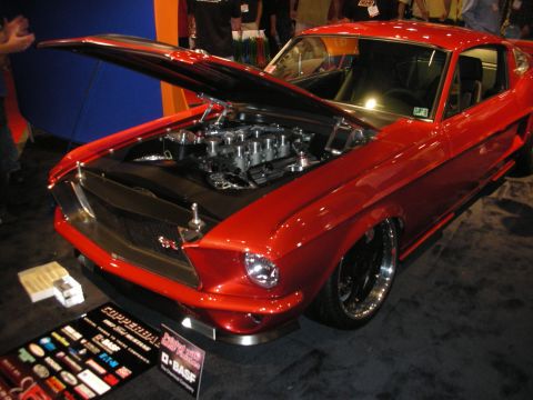 Red classic fastback with open hood showing individual-runner V8 on black wheels
