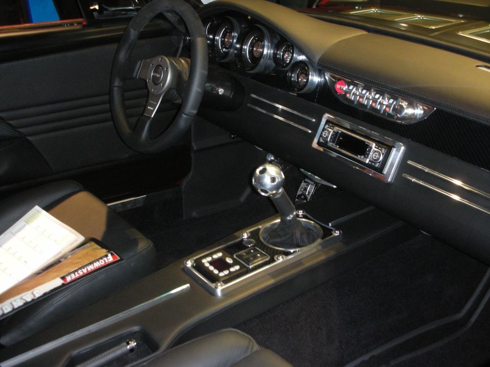 Custom black car interior with chrome console, automatic shifter, and four round gauges