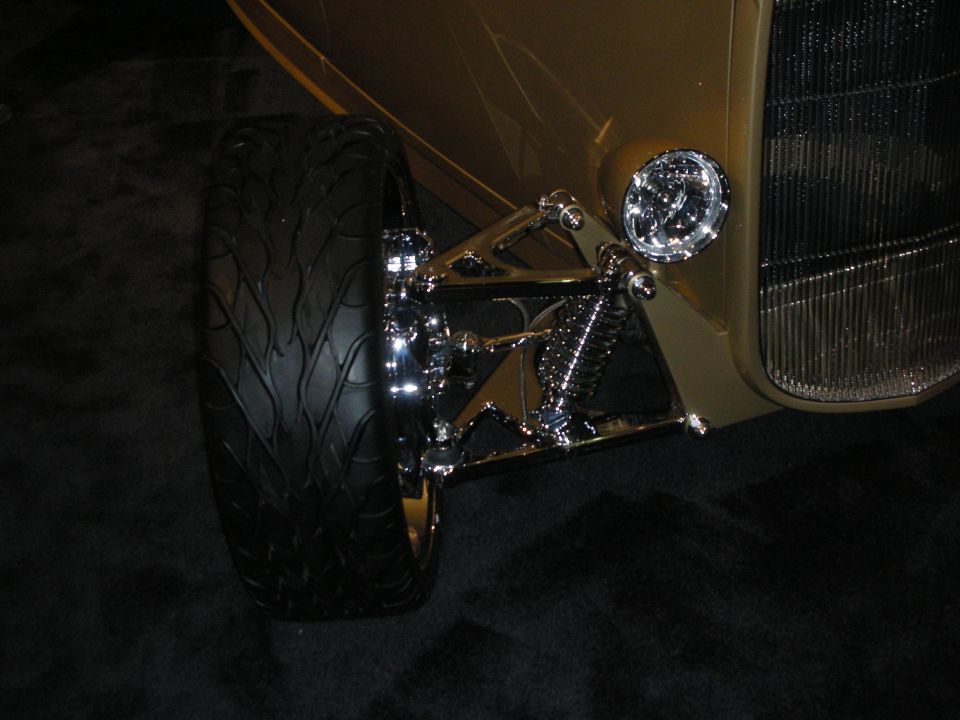 Front suspension and wheel of a gold hot rod with chrome shock and headlight