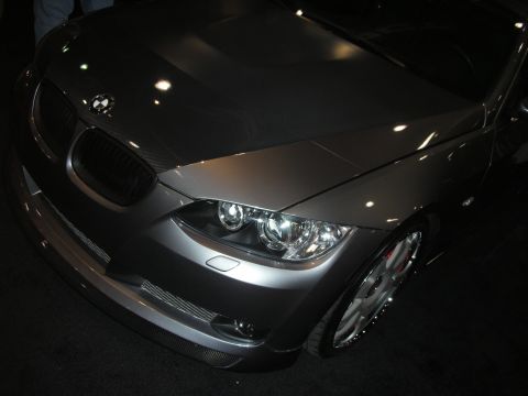 Front end of a gray BMW with kidney grille and dual round headlights, hood up