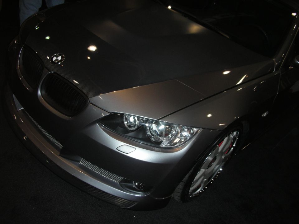 Front end of a gray BMW with kidney grille and dual round headlights, hood up