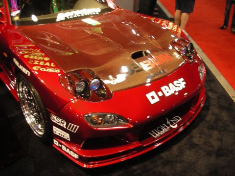 Front of a red sports coupe with carbon hood, sticker decals, and pop-up lights