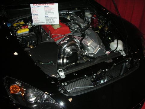 Supercharged engine bay of black Honda S2000 with red valve cover and spec card