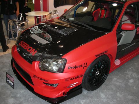 Red and black Subaru WRX STI with Seibon carbon hood at indoor show