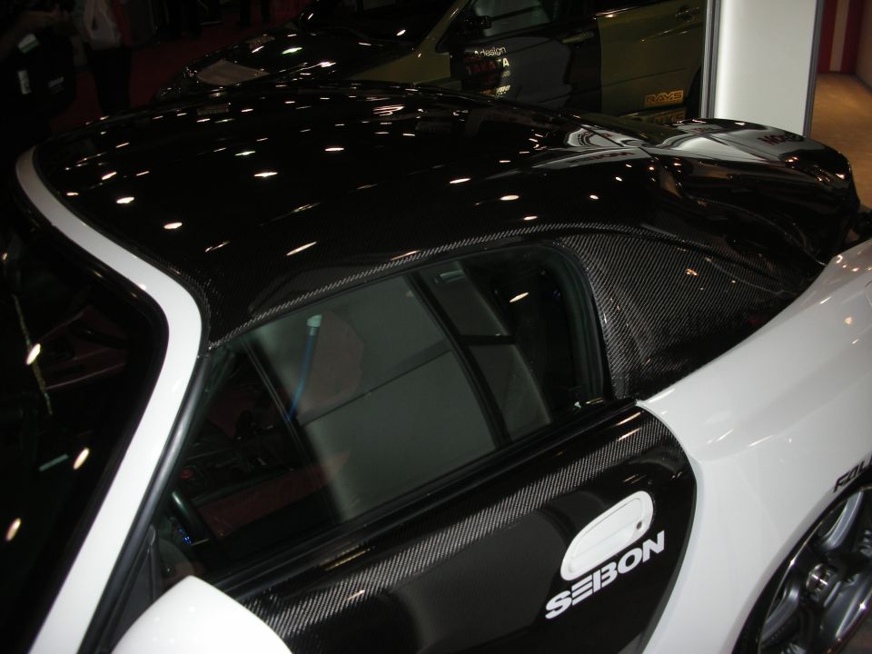 Carbon-fiber roof of white sports car with Seibon logo at indoor show