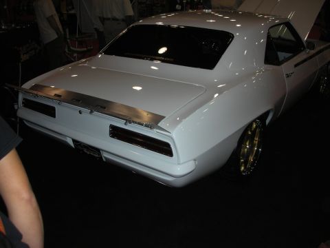 Rear of white 1969 Chevrolet Camaro with gold wheels at indoor show