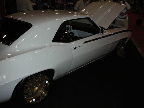 Side profile of white 1969 Camaro custom with gold wheels and open hood