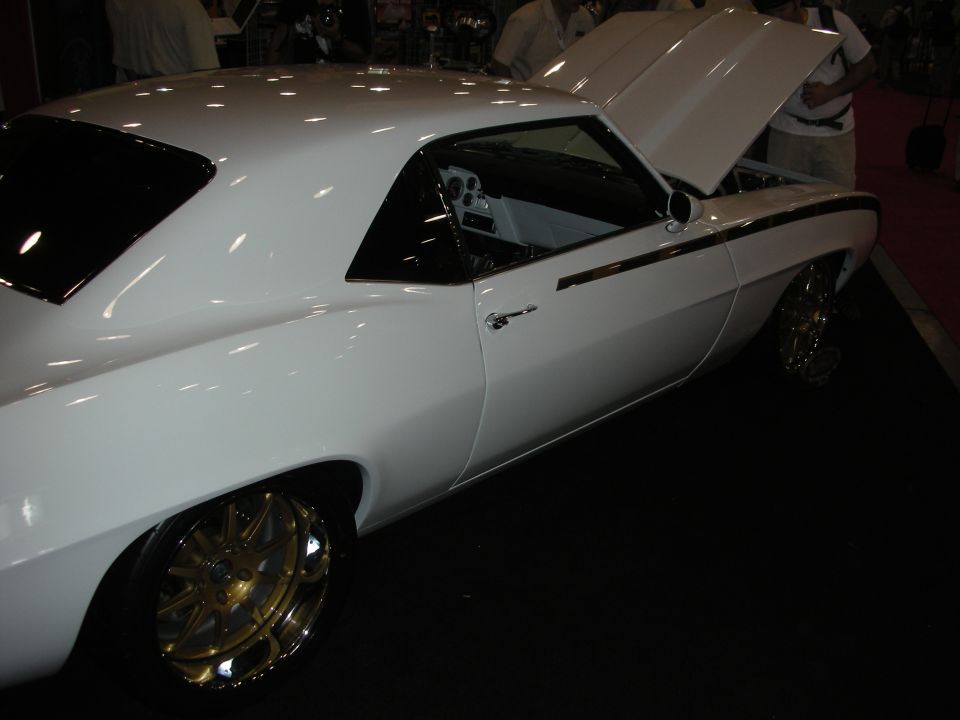 Side profile of white 1969 Camaro custom with gold wheels and open hood