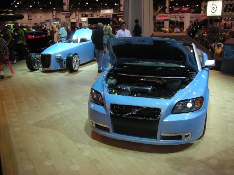 Light blue Volvo C70 convertible and blue hot rod roadster at indoor show