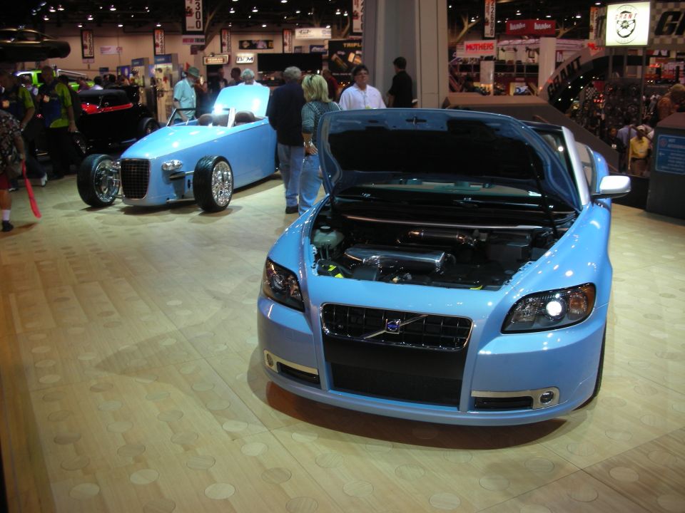 Light blue Volvo C70 convertible and blue hot rod roadster at indoor show