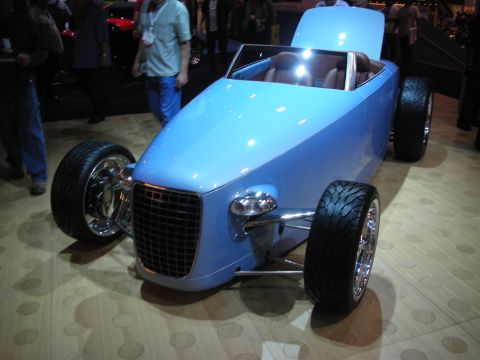 Light blue custom hot rod roadster with grille and large wheels at show