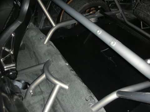 Interior tube-frame roll cage tubing over carpeted floor of custom car