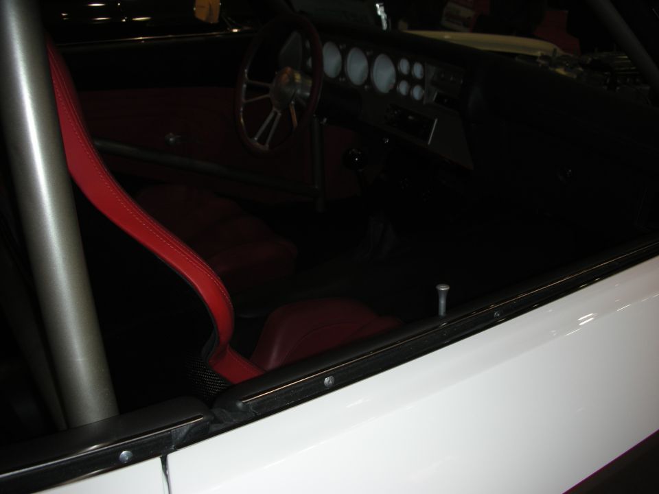 Dim interior of custom car with red seats, round gauges, and roll bar