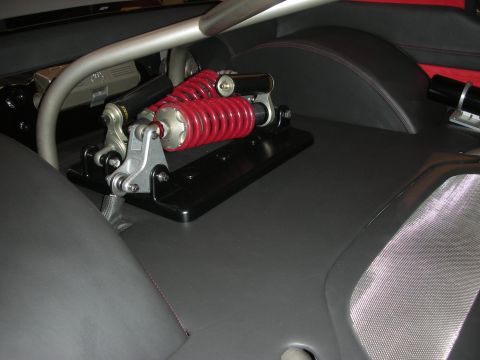 Red coilover spring suspension unit mounted behind custom car seats