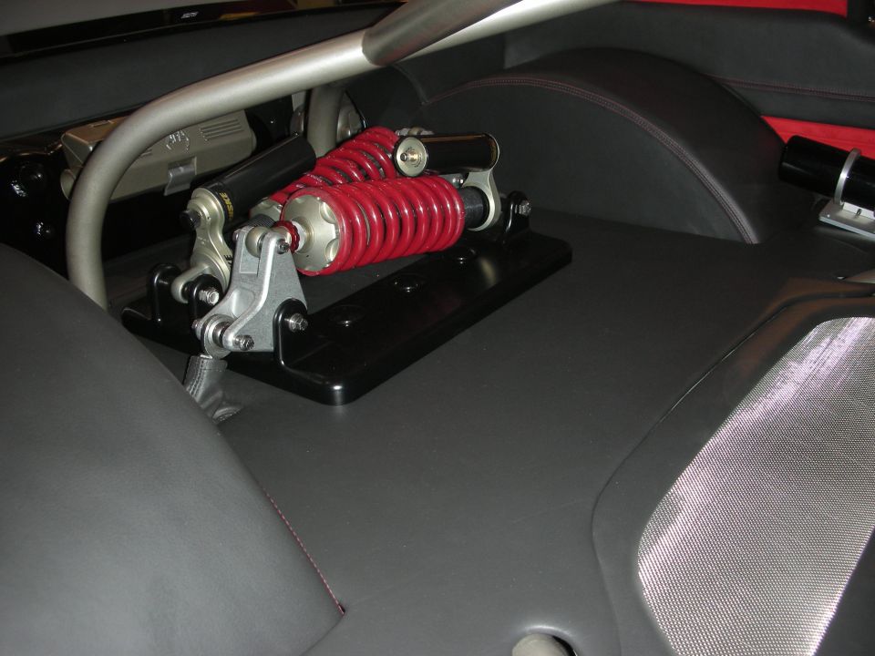 Red coilover spring suspension unit mounted behind custom car seats