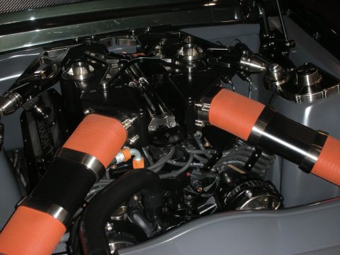1998 Ford Crown Victoria - custom engine bay packed with orange silicone hoses, black components and polished velocity stacks under gray bodywork.