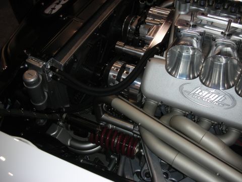 1998 Ford Crown Victoria - Close detail of a custom engine bay showing polished velocity stacks, a Hartley-branded cover and a red coilover spring.