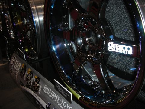 1998 Ford Crown Victoria - Polished chrome multi-spoke alloy wheels on a display stand at a booth, with a banner reading Williams-Toyo.