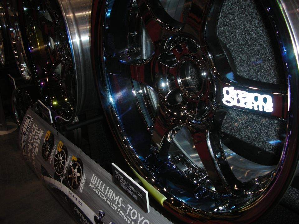 Polished chrome multi-spoke alloy wheels displayed on a booth stand