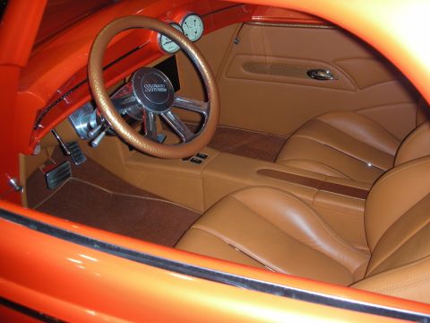 1998 Ford Crown Victoria - tan leather interior of an orange custom car, showing a banjo-style steering wheel, bucket seats and round gauges.