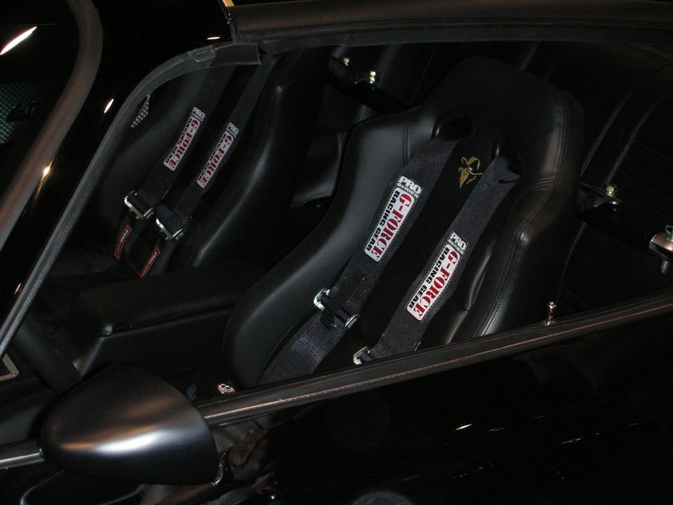 Black racing bucket seats with Crow harnesses inside a dark interior