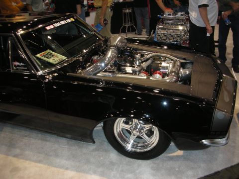 1998 Ford Crown Victoria - black muscle car sits low on polished five-spoke wheels with a supercharged engine and intercooler exposed through the hood.