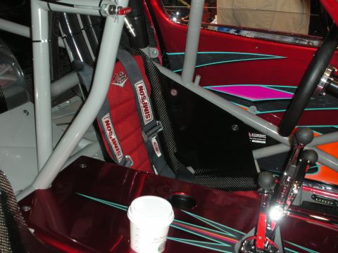 1998 Ford Crown Victoria - Roll-caged red show-car interior with a Simpson racing harness, dual shifters, pinstriping and a paper cup on the floor.