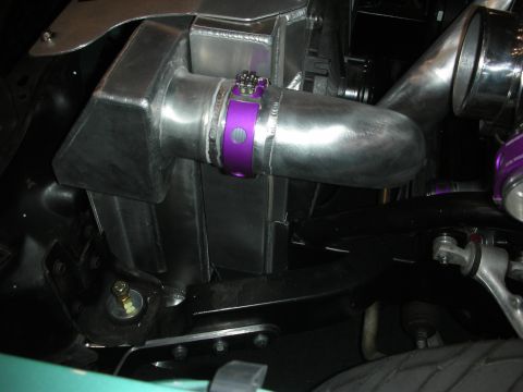 1998 Ford Crown Victoria - Underhood view of a bare-aluminum intercooler joined to a polished charge pipe with a purple clamp near the suspension.