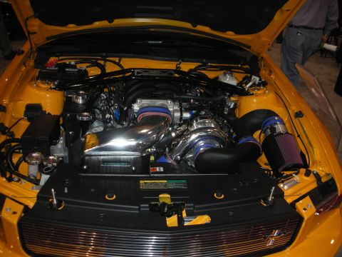 1998 Ford Crown Victoria - Yellow Ford Mustang engine bay fitted with a centrifugal supercharger, chrome piping and a cone air filter.