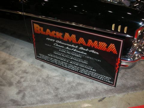 1998 Ford Crown Victoria - ornate 'Black Mamba' plaque crediting a 1957 Chevrolet Bel Air build sits against the side of a glossy black show car.