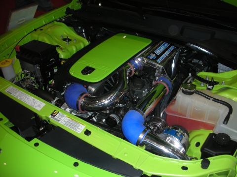 1998 Ford Crown Victoria - Lime-green car engine bay with a green plenum cover, polished charge piping, blue couplers and a supercharger.