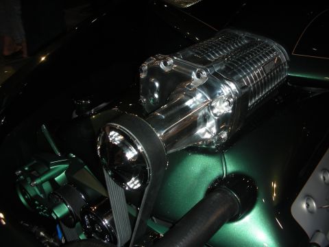 1998 Ford Crown Victoria - Close-up of a chrome twin-screw supercharger with belt drive mounted on an engine in a metallic green engine bay.