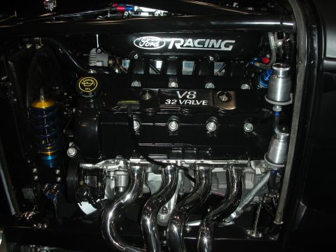 1998 Ford Crown Victoria - Front view of a Ford Racing 32-valve V8 dressed in black, with polished chrome headers and a gold coilover shock alongside.