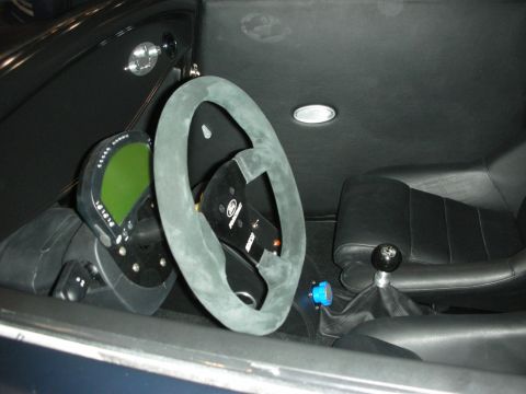 1998 Ford Crown Victoria - custom cockpit with a suede-rimmed racing steering wheel, digital dash and black shifter inside a hot rod with dark trim.