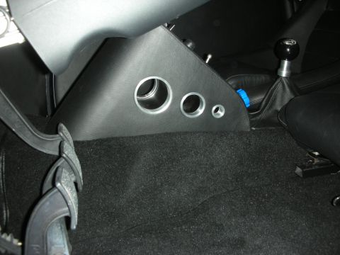 1998 Ford Crown Victoria - black leather transmission-tunnel panel with three machined round vents sits beside a shifter boot above dark carpet.