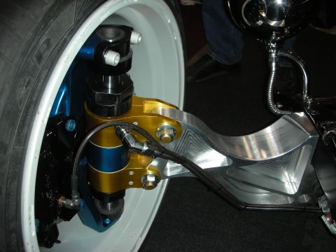 1998 Ford Crown Victoria - polished billet suspension arm with a gold-bodied coilover and braided line mounts to a white-painted wire wheel.