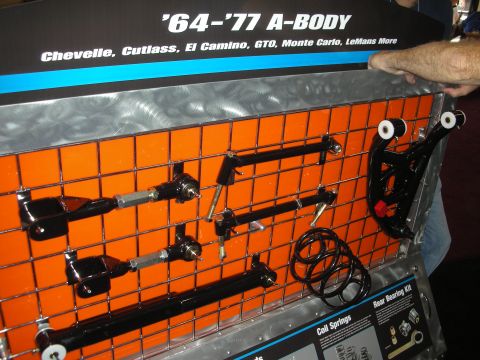 1998 Ford Crown Victoria - vendor display board titled '64-'77 A-Body shows black suspension control arms and links mounted over an orange grid.