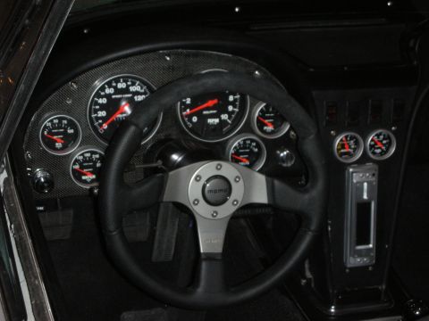 1998 Ford Crown Victoria - custom dashboard with a black MOMO steering wheel framing a cluster of large round white-numbered gauges set into a carbon panel.