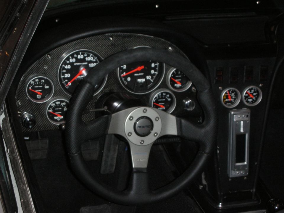 Custom dashboard with MOMO steering wheel and large round white-numbered gauges in carbon panel