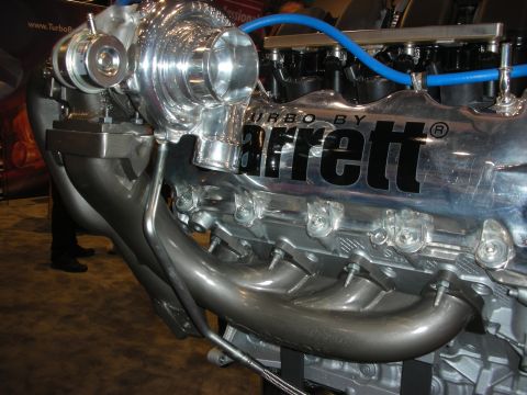 1998 Ford Crown Victoria - polished turbocharger bolted to swept headers on a chrome inline engine head stamped Turbo by Garrett, shown on display.