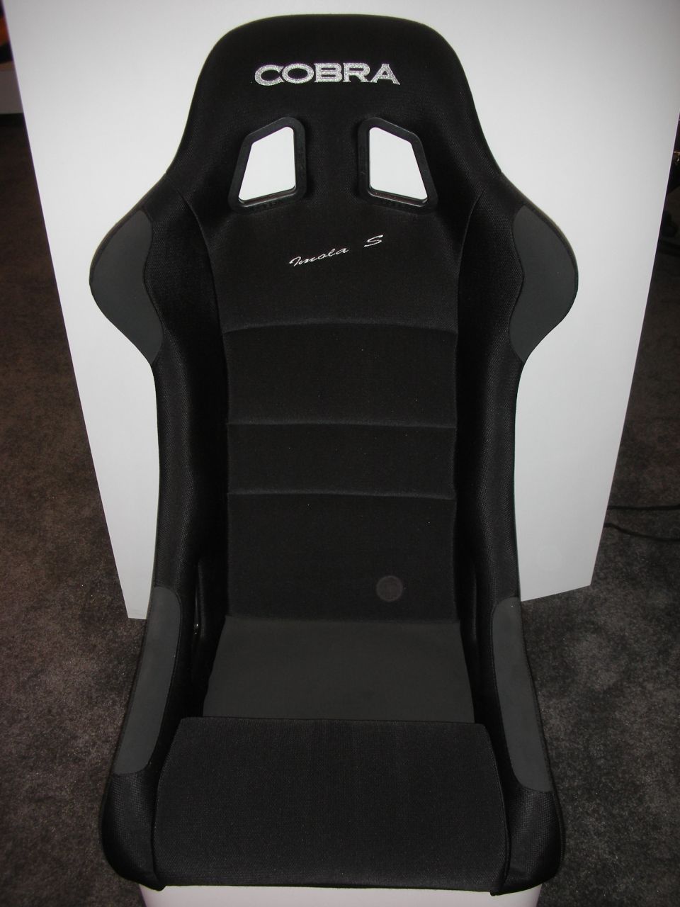 Black Cobra racing bucket seat with embroidered logo standing against a white backdrop