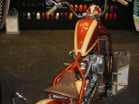 1998 Ford Crown Victoria - Custom chopper motorcycle with orange metalflake tank, ape-hanger bars and a tooled brown leather seat on display.