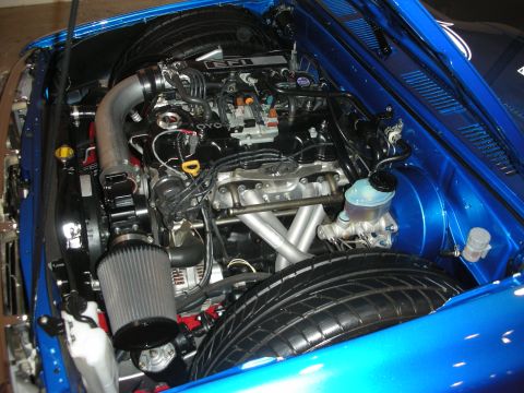 1998 Ford Crown Victoria - Detailed engine bay of a bright blue sports car showing a transverse engine, cone air filter and tidy braided plumbing.